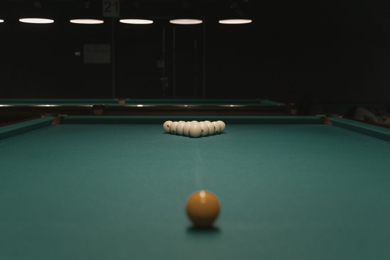 Classic billiards table setup with cue ball aimed for a perfect break in a dimly lit room.